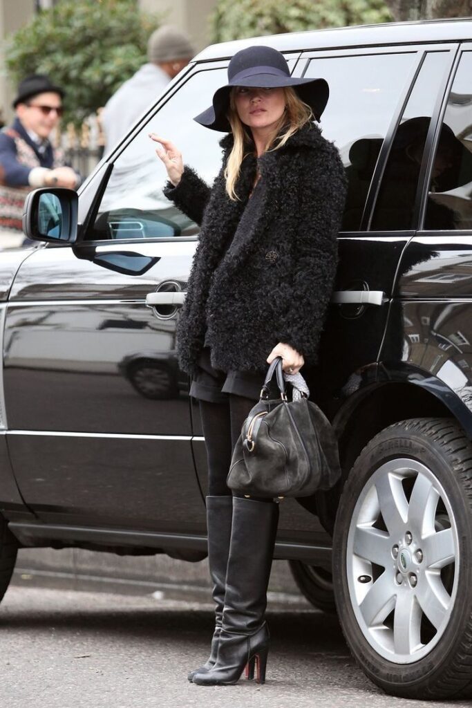 Kate Moss Wearing Wide-Brimmed Statement Hat, Black Fur Coat, Black Leather Knee-High Boots and a Black Leather Oversized Handbag